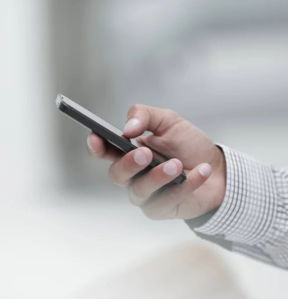 Primer plano. Un hombre sostiene un teléfono inteligente . — Foto de Stock