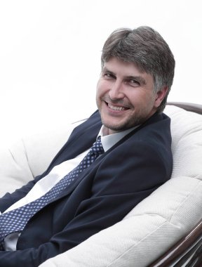 yan görünümü. Rahat koltuk kameraya bakarak oturan işadamı