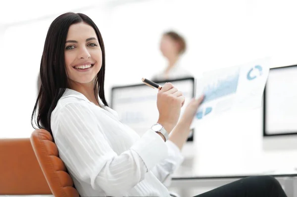 Glimlachende zakenvrouw met financiële documenten zitten aan een bureau. — Stockfoto