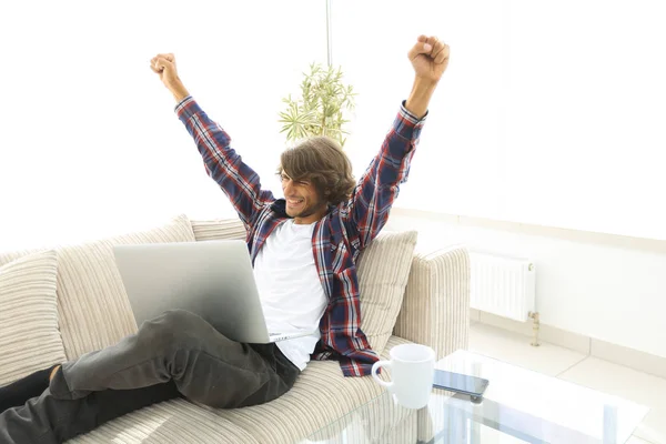Šťastný mladý muž dívá na obrazovce přenosného počítače — Stock fotografie