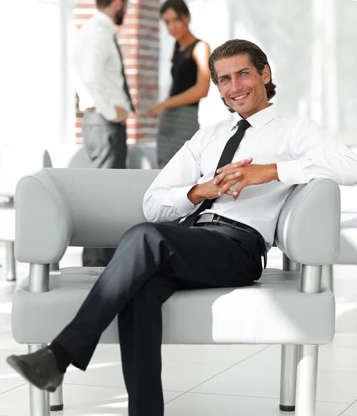 Улыбающийся бизнесмен, сидящий в кресле — стоковое фото