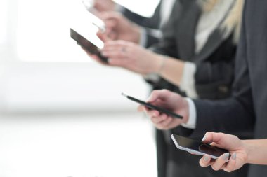 İş ekibi akıllı telefonlarının ekranlarına bakıyor.