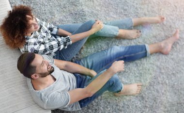 yeni bir oturma odasında bir halı üzerinde oturan yeni evli çift