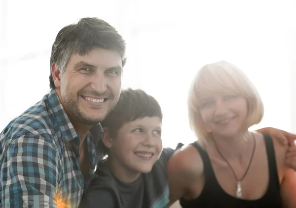 Os pais e seu filho se sentam enfiados na sala de estar e sorrindo — Fotografia de Stock