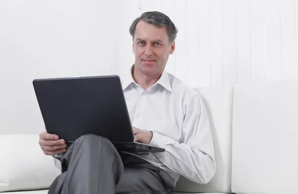 Erfolgreicher Geschäftsmann am Laptop auf dem Sofa sitzend — Stockfoto