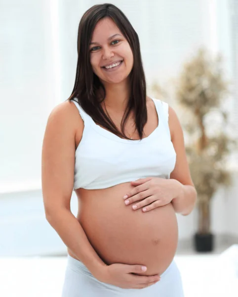 Portret van jonge zwangere vrouw op een lichte achtergrond. — Stockfoto