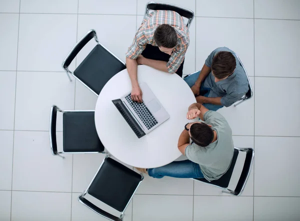 group of people with gadgets sitting at a round table