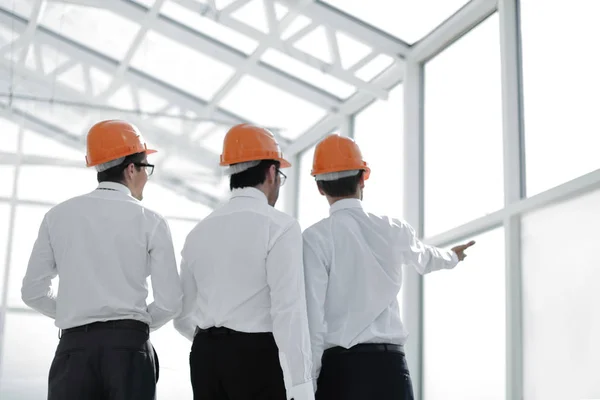 Hombres de negocios en cascos de protección de pie en la nueva oficina —  Fotos de Stock