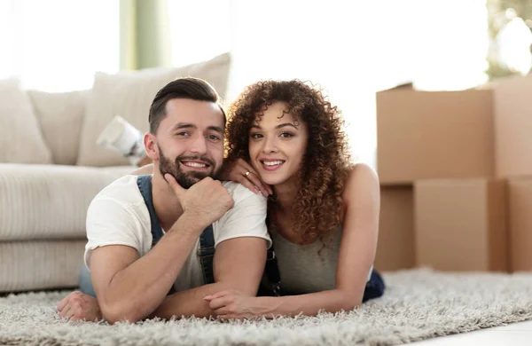 Casal feliz deitado no tapete no fundo borrado — Fotografia de Stock