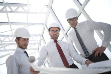 Üç mimar yeni bir proje için çizimleri tartışıyor