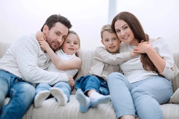 Föräldrar krama sina barn som sitter i soffan — Stockfoto