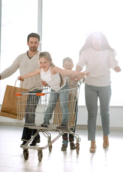 Familia divertida con bolsas de compras y carrito de compras —  Fotos de Stock
