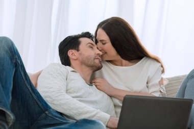 Erkek ve kız arkadaşı evde dizüstü bilgisayarla sohbet ediyorlar.