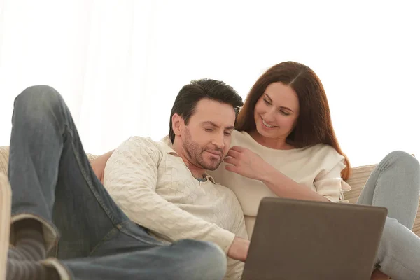 Gelukkige paar zittend op de Bank in haar armen, kijken naar laptop — Stockfoto