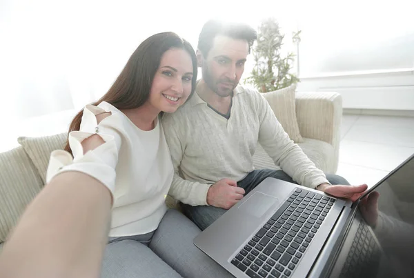 Pareja casada con portátil sentado en el sofá — Foto de Stock