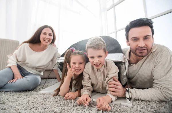 Pais felizes brincam com crianças em uma tenda na sala de estar — Fotografia de Stock