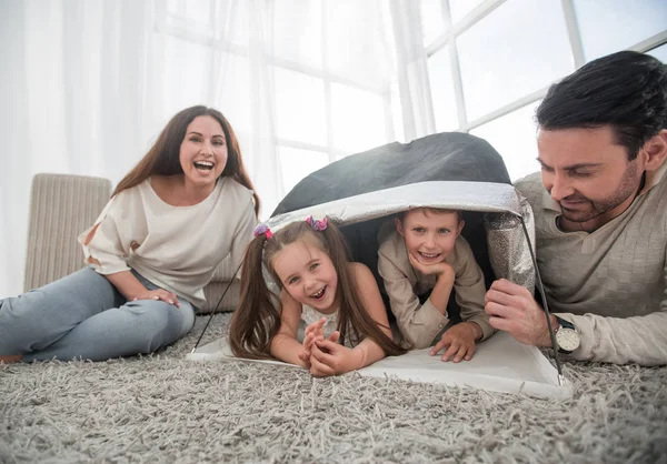 Happy parents play with children in a tent in the living room — Stock Photo, Image