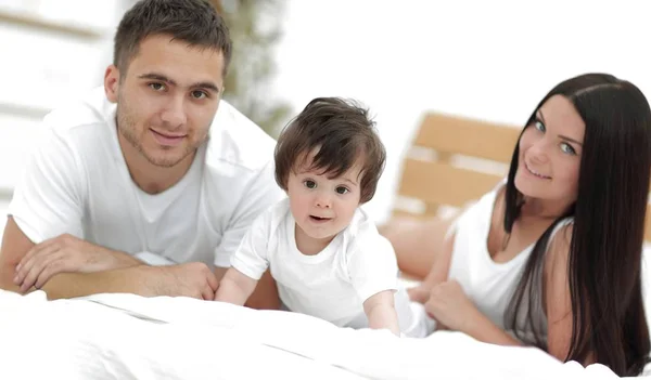 Retrato de familia joven y feliz acostados en la cama juntos —  Fotos de Stock