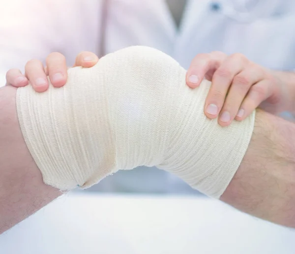 Traumatologista, aplicando uma bandagem no joelho — Fotografia de Stock
