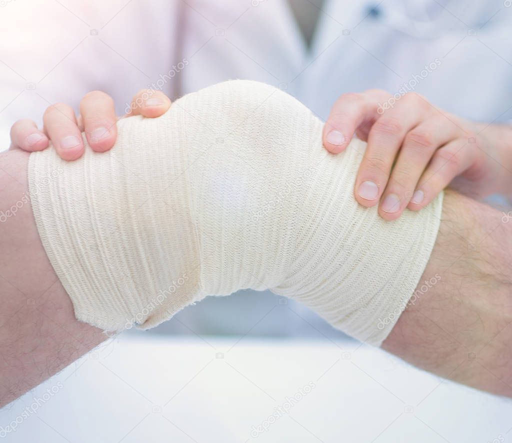 traumatologist ,applying a bandage on the knee