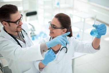 Kapatın. Araştırmacılar şişedeki sıvıyı tartışıyorlar.