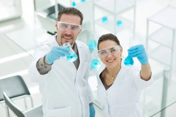 Glad vetenskapsman och assistent visar tube med vätska — Stockfoto