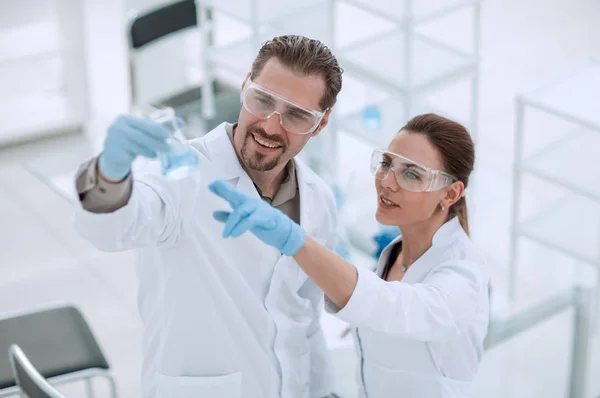 Scientist and assistant look at the liquid in the flask — Stock Photo, Image