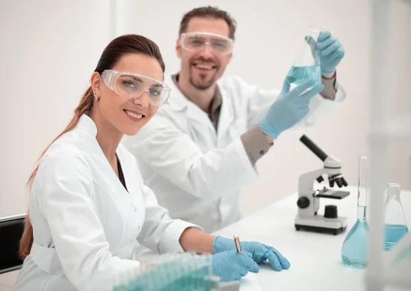 Женщина-ученый и ее ассистент работают в лаборатории — стоковое фото