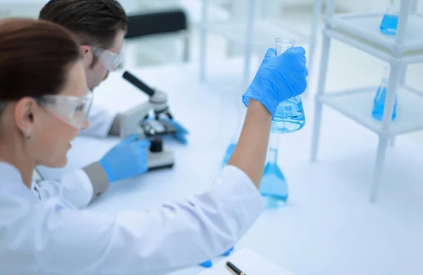 Young female researcher and her senior supervisor are doing investigations with test tubes — Stock Photo, Image