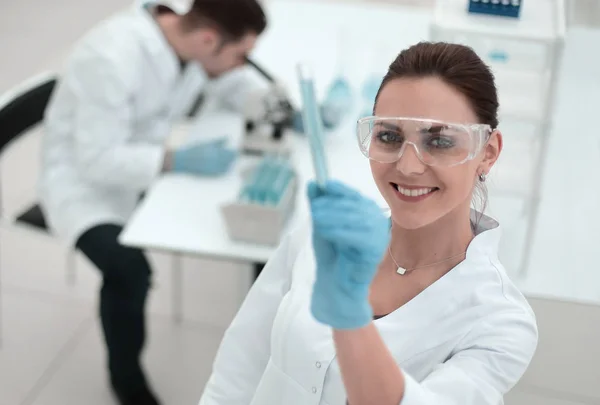 Mujer científica sonriente mirando el tubo con los resultados del análisis — Foto de Stock