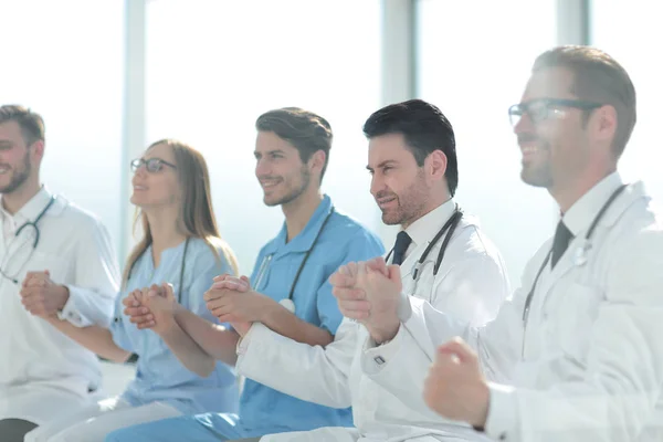 Lekarze siedzieć z rzędu i trzymać się za ręce z siebie — Zdjęcie stockowe