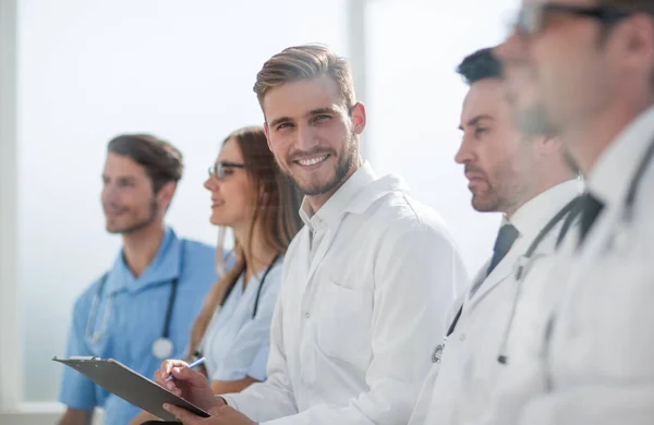 Närbild av leende läkare sitter med sitt team — Stockfoto