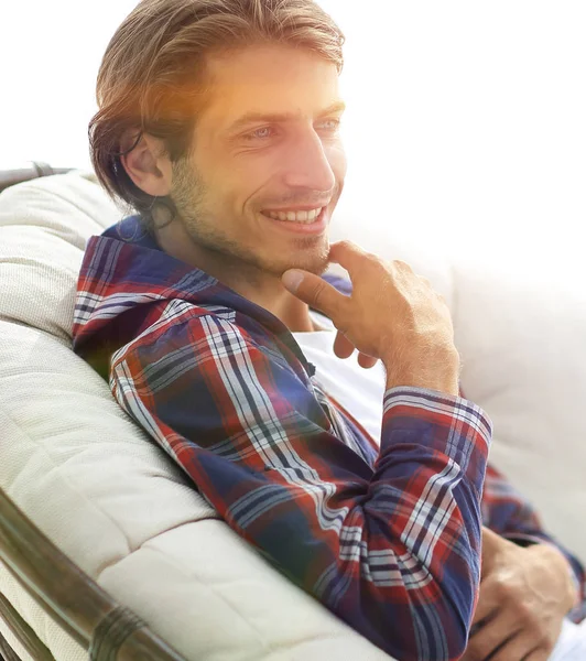 Primer plano. sonriente chico está descansando en una silla cómoda grande — Foto de Stock