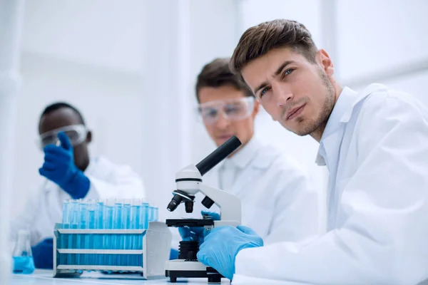 Grupo de jóvenes científicos sentados en la mesa de laboratorio — Foto de Stock