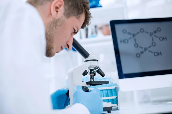 Scientist looking through a microscope in a laboratory — Stock Photo, Image