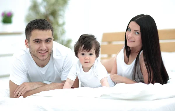 Retrato de familia joven y feliz acostados en la cama juntos — Foto de Stock