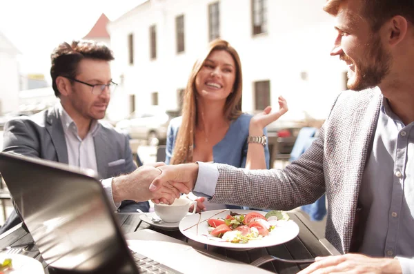 Colegas de apretón de manos en una mesa en un café de la calle —  Fotos de Stock