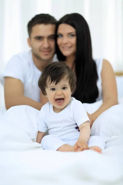 Happy couple and son sitting in bed — Stock Photo, Image