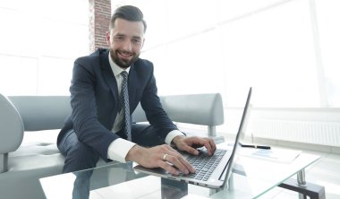 Modern ofis dizüstü bilgisayarda çalışan başarılı erkeğin