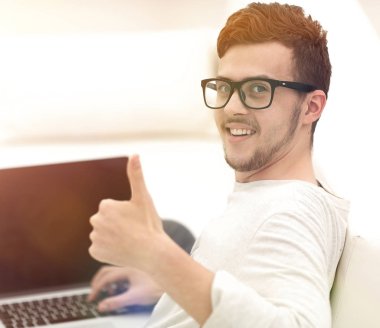 açık belgili tanımlık laptop önünde oturan ve gösterilen modern genç yukarı başparmak