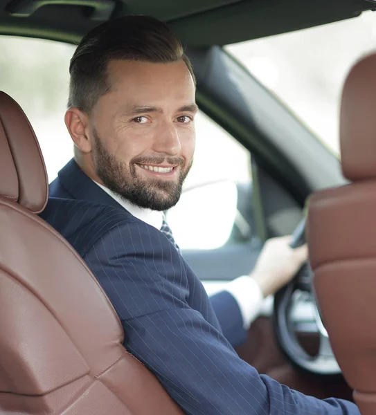 Бизнесмен, сидящий за рулем автомобиля и смотрящий в камеру — стоковое фото