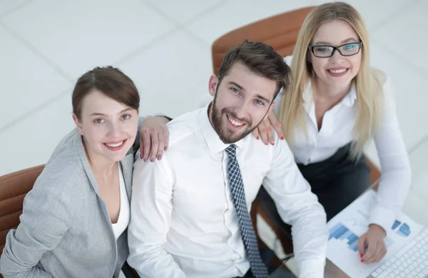 Erfolgreiches Business-Team sitzt am Tisch und blickt in die Kamera. — Stockfoto