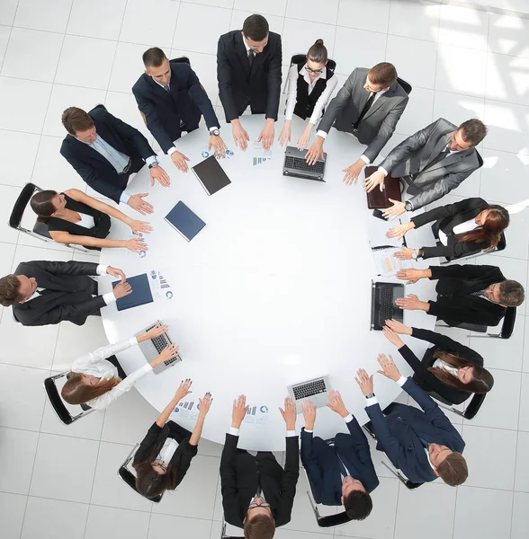 Grupo de empresários sentados à mesa redonda, e colocando as palmas das mãos sobre a mesa — Fotografia de Stock