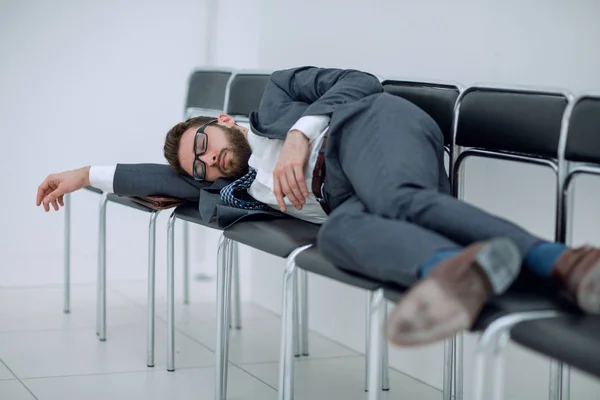 Homem de negócios cansado deitado em cadeiras e esperando por uma entrevista — Fotografia de Stock