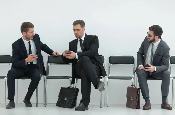 Funcionários com smartphones sentados no corredor do escritório — Fotografia de Stock