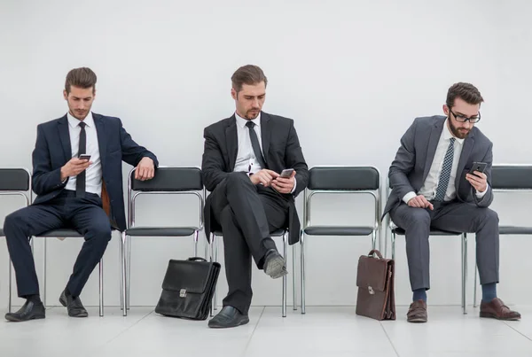 Geschäftsleute mit Mobiltelefonen sitzen im Büroflur — Stockfoto