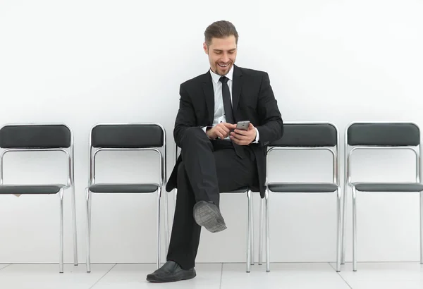 Επιχειρηματίας με κινητό κάθεται στο γραφείο διάδρομο — Φωτογραφία Αρχείου