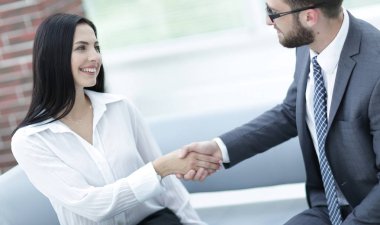 Yöneticisi ve müşteri ofis lobisinde otururken el sıkışma.