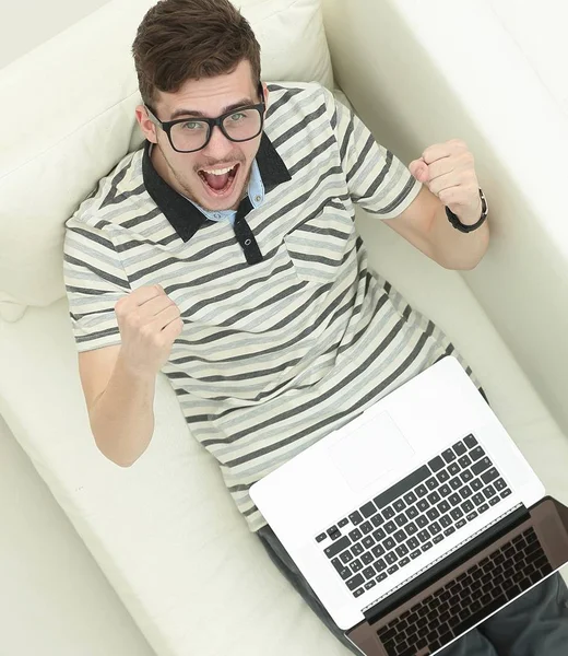 Happy modern man looks at the laptop sitting on the couch. — Stock Photo, Image