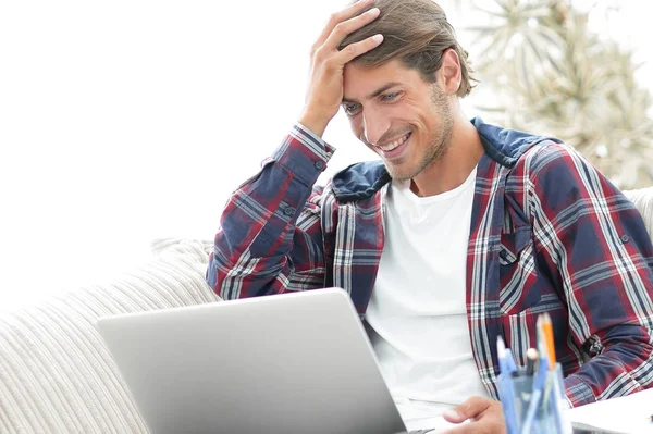 Χαρούμενος νεαρός άνδρας που εργάζεται με φορητό υπολογιστή από το σπίτι. — Φωτογραφία Αρχείου